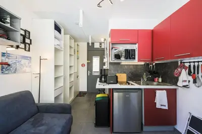 a small kitchen with red cabinets and a couch at Résidence Bellatrix - maeva Home - Studio 2 Personnes - Confort MAE-2104 in Flaine