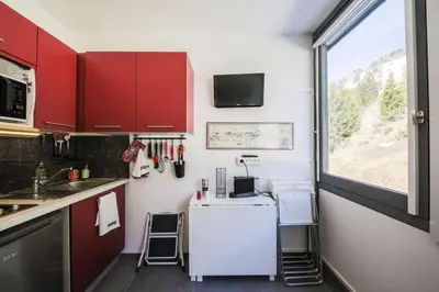 a kitchen with red cabinets and a white refrigerator at Résidence Bellatrix - maeva Home - Studio 2 Personnes - Confort MAE-2104 in Flaine