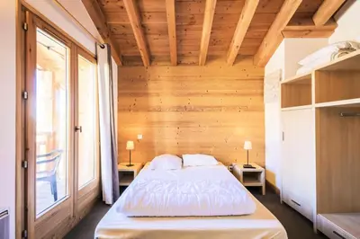 a bedroom with a bed in a room with wooden walls at Résidence Refuge du Golf - maeva Home - Chalet 4 Pièces 8 Personnes - Prestige MAE-3884 in Arâches-la-Frasse