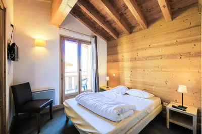 a bedroom with a bed and a chair and a window at Résidence Refuge du Golf - maeva Home - Chalet 4 Pièces 8 Personnes - Prestige MAE-3884 in Arâches-la-Frasse