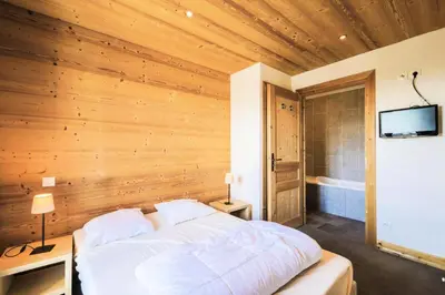 a bedroom with a bed with a wooden wall at Résidence Refuge du Golf - maeva Home - Chalet 4 Pièces 8 Personnes - Prestige MAE-3884 in Arâches-la-Frasse