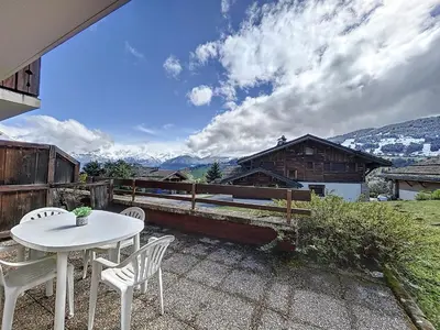 a white table and chairs on a patio with mountains at Appartement Mont Blanc : 2 chambres, terrasse, parking et équipements modernes - FR-1-560-131 in Demi-Quartier