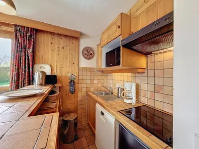 a kitchen with wooden cabinets and a counter top at Appartement Mont Blanc : 2 chambres, terrasse, parking et équipements modernes - FR-1-560-131 in Demi-Quartier