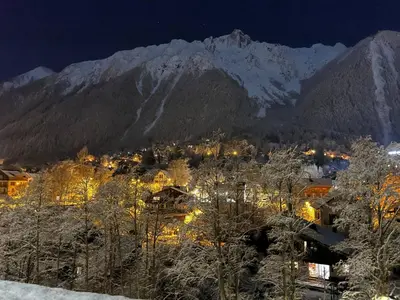 a town at night with a snow covered mountain at Appartement 
