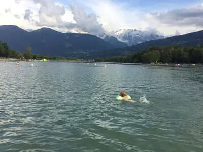 a child swimming in a lake with a ball at Studio de 31m² idéalement situé aux pieds des remontées mécaniques été/hiver in Saint-Gervais-les-Bains