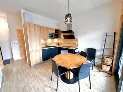 a kitchen and dining room with a wooden table and chairs at Studio de 31m² idéalement situé aux pieds des remontées mécaniques été/hiver in Saint-Gervais-les-Bains