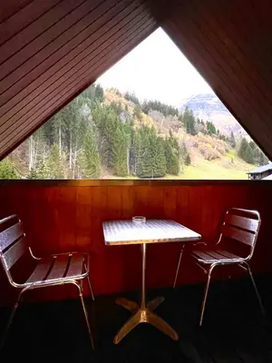 a table and two chairs in a room with a window at Al_titude1138 in Les Contamines-Montjoie