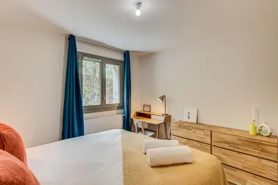 a bedroom with a bed with blue curtains and a desk at White Pearl A03 - Alpes Travel - Central Chamonix - Sleeps 2-4 in Chamonix-Mont-Blanc