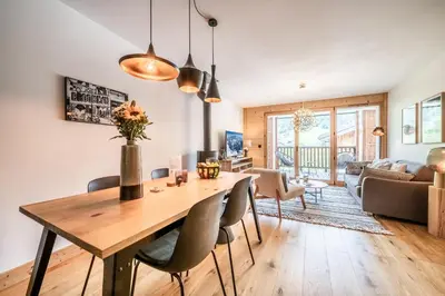 a dining room and living room with a wooden table and chairs at Apartment Opale Megève - by EMERALD STAY in Megève