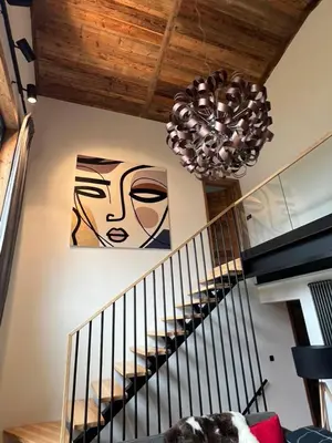 a room with a staircase with a chandelier at Chalet 8 Etoiles in Chamonix-Mont-Blanc