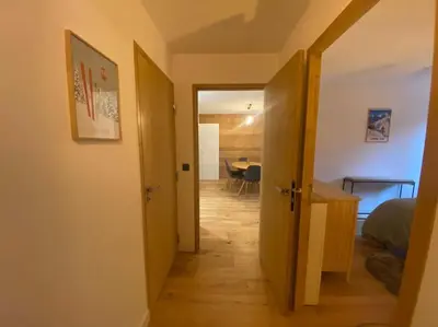 a hallway with a door open to a room with a table at Appartement T2 de Standing Neuf 6-8 personnes avec Balcon et Jardinet au Pied des Pistes à Combloux in Combloux