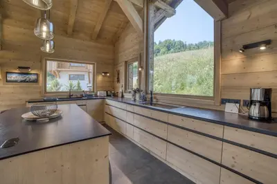 a kitchen with wooden walls and a large window at Chalet familial vue MontBlanc in Saint-Gervais-les-Bains