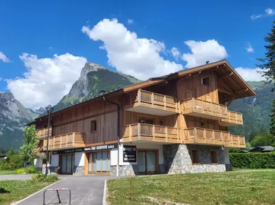 a large wooden building with a balcony and mountains at Saskya 5 65m2, 2 bedrooms, next to the ski lift in Samoëns