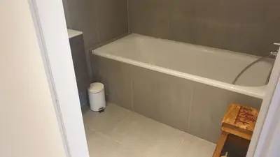 a bathroom with a bath tub and a trash can at Duplex les Myrtilles LES CARROZ centre station in Les Carroz d'Araches