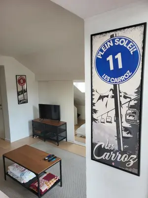 a living room with a sign on the wall at Duplex les Myrtilles LES CARROZ centre station in Les Carroz d'Araches