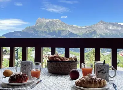 a table with a basket of pastries and a view of mountains at L'Appartement des Pistes in Saint-Gervais-les-Bains