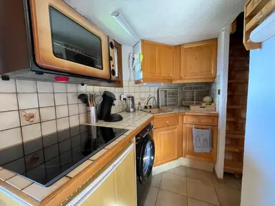 a small kitchen with wooden cabinets and a dishwasher at L'Appartement des Pistes in Saint-Gervais-les-Bains