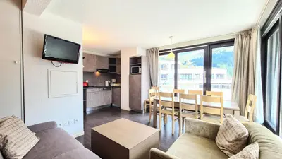a living room with a couch and a table and a kitchen at Résidence Les Terrasses De Veret - Appartement lumineux · Au pied des pistes · Piscine · Parking inclus · Spa MAE-1651 in Magland