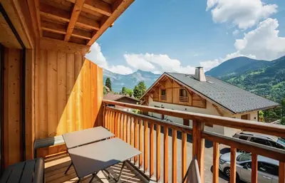 a balcony with a chair and a view of a house at Chalet familial de 6 chambres dominant Saint-Gervais classé 4 étoiles in Saint-Gervais-les-Bains