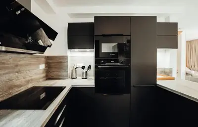 a kitchen with black cabinets and black appliances at Chalet familial de 6 chambres dominant Saint-Gervais classé 4 étoiles in Saint-Gervais-les-Bains