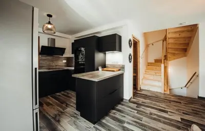 a kitchen with black cabinets and a wooden floor at Chalet familial de 6 chambres dominant Saint-Gervais classé 4 étoiles in Saint-Gervais-les-Bains