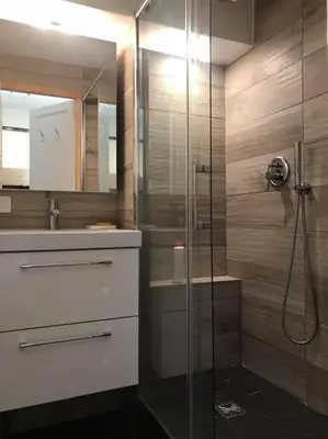 a bathroom with a shower with a glass door at La marmotte: Vue Mont Blanc, terrasse, parking in Combloux