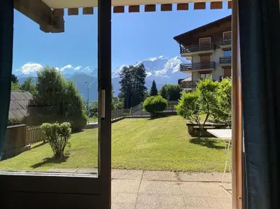 a view from a window of a yard with a mountain at La marmotte: Vue Mont Blanc, terrasse, parking in Combloux