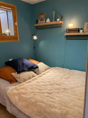 a bedroom with a bed and a blue wall at La marmotte: Vue Mont Blanc, terrasse, parking in Combloux