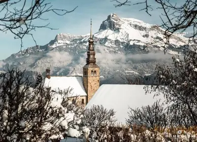 a church with a snow covered mountain in the background at La marmotte: Vue Mont Blanc, terrasse, parking in Combloux