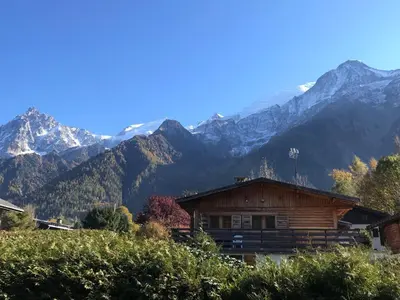 a log cabin with mountains in the background at Superbe chalet 10 personnes 5 chambres Les Houches in Les Houches