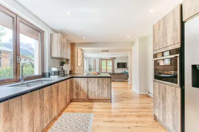 a kitchen with wooden cabinets and a large window at Sauna Bain Nordique Cinéma Vue Montange in Chamonix-Mont-Blanc