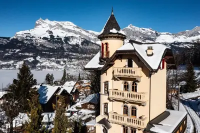 a house in the snow with mountains in the background at Villa la tourelle in Saint-Gervais-les-Bains