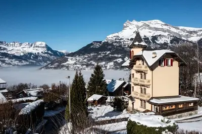 a house in the snow with mountains in the background at Villa la tourelle in Saint-Gervais-les-Bains