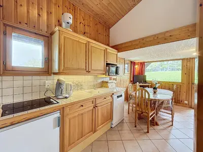 a kitchen with wooden cabinets and a table and a dining room at Charmant 4 pièces avec terrasse face Mont Blanc, proche téléski, village et garage sécurisé - FR-1-560-133 in Combloux