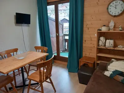 a dining room with a table and a clock on the wall at Joli studio à St Gervais les bains in Saint-Gervais-les-Bains