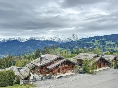 a large log cabin with mountains in the background at Studio cosy au pied des pistes avec parking à Combloux - FR-1-560-137 in Combloux