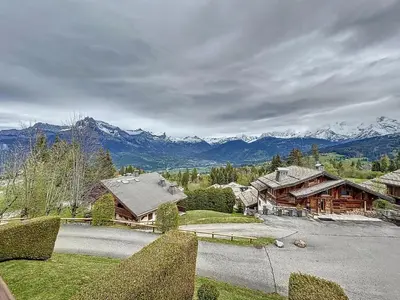 a house with mountains in the background with a driveway at Studio cosy au pied des pistes avec parking à Combloux - FR-1-560-137 in Combloux