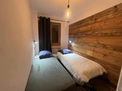 two beds in a room with a wooden wall at I love Megève in Megève