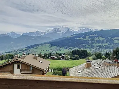 a house on a hill with mountains in the background at Charmant appart 3 pièces proche des pistes avec parking et terrasse - FR-1-560-140 in Combloux