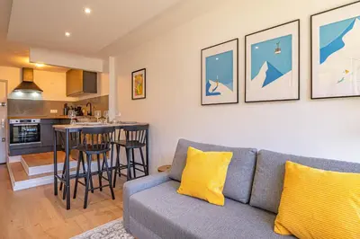 a living room with a couch and a kitchen at Chamois Blanc Rosières- bright 1 bed apartment with amazing views in Chamonix-Mont-Blanc