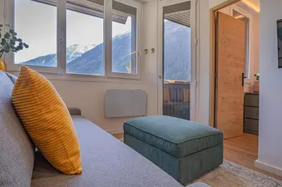 a living room with a couch and a chair and windows at Chamois Blanc Rosières- bright 1 bed apartment with amazing views in Chamonix-Mont-Blanc