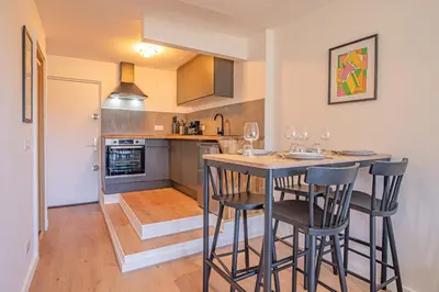 a kitchen with a bar with chairs and a table at Chamois Blanc Rosières- bright 1 bed apartment with amazing views in Chamonix-Mont-Blanc
