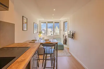 a kitchen with a counter and a bar with stools at Chamois Blanc Rosières- bright 1 bed apartment with amazing views in Chamonix-Mont-Blanc