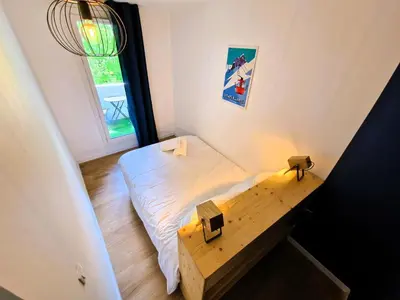 a small bedroom with a bed and a wooden table at Appart Les Cosmiques, Vue Mont Blanc - Aiguille du Midi in Chamonix-Mont-Blanc
