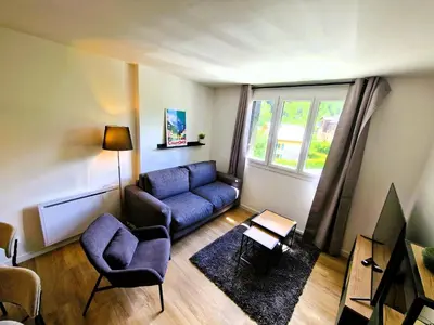 a living room with a blue couch and a window at Appart Les Cosmiques, Vue Mont Blanc - Aiguille du Midi in Chamonix-Mont-Blanc