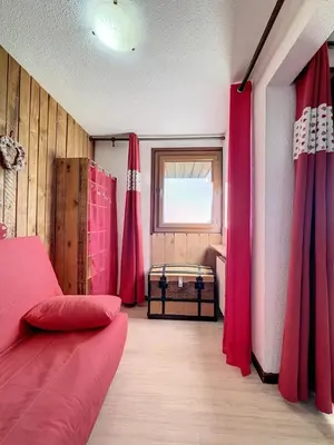 a room with red curtains and a bed and a window at Studio Samoëns 1600 station de ski in Samoëns