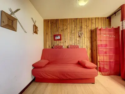 a red couch in a room with wooden walls at Studio Samoëns 1600 station de ski in Samoëns