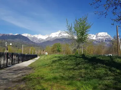 a field with a fence and snow covered mountains at Appartement l'Étoile pour 1 à 4 personnes in Sallanches