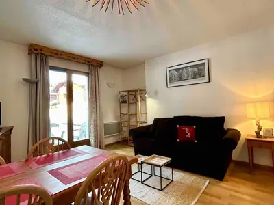 a living room with a black couch and a table at Studio confortable avec parking et animaux admis - FR-1-629-139 in Samoëns
