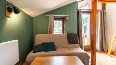 a bedroom with green walls and a bed with a wooden table at LES ARCADES - 310 - Appt accueillant 4-6 pers in Morillon